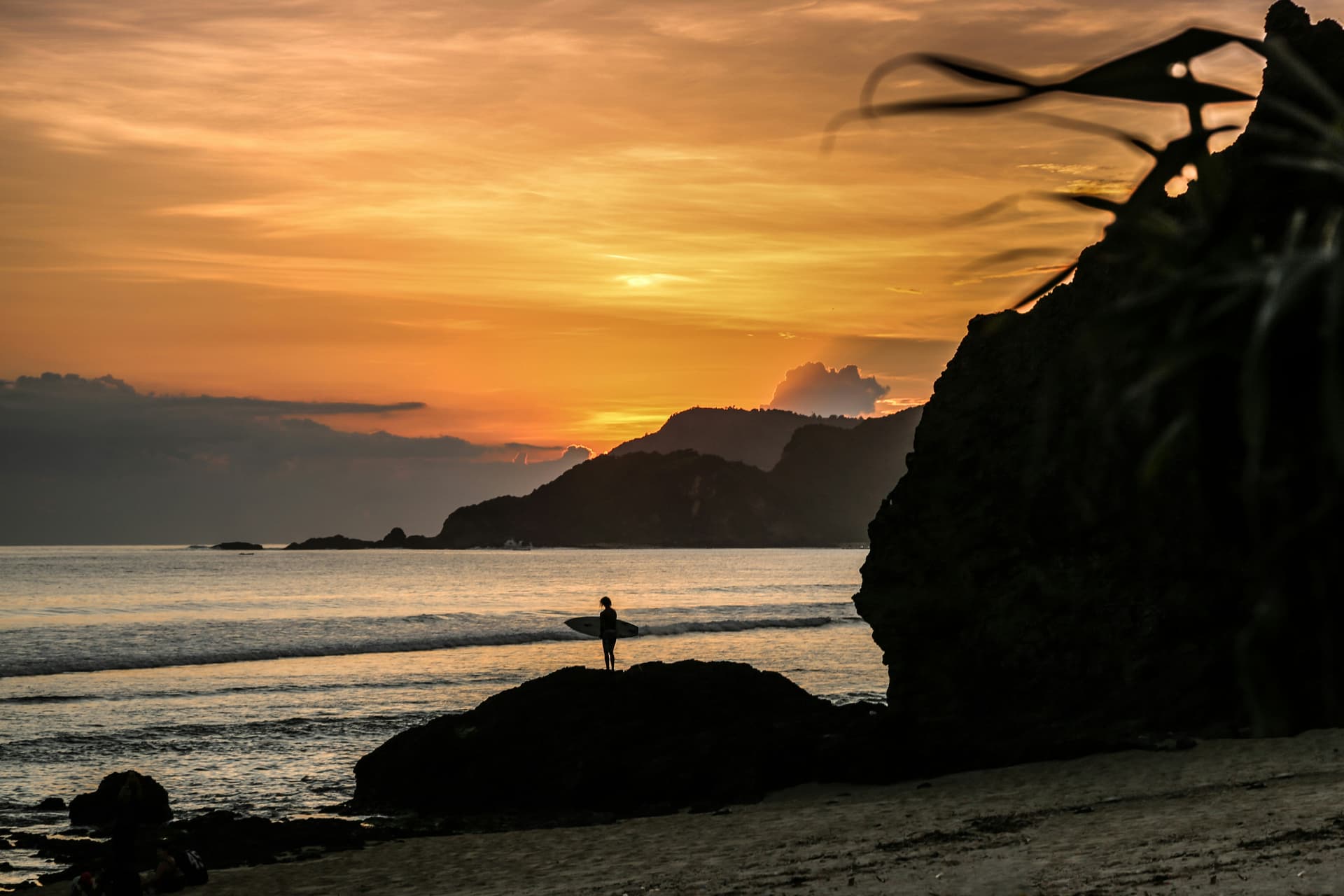 A lone figure on the shore at sunset on the Lombok coast