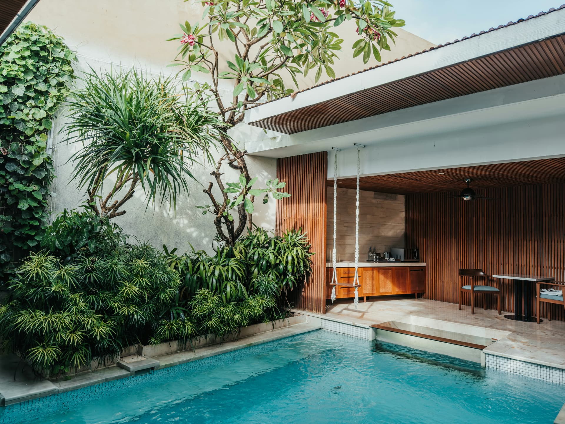 A villa pool framed by a timber pavilion and tropical planting